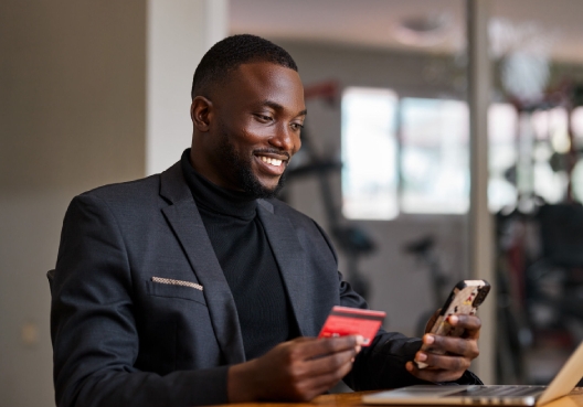 A gentleman wearing a suit and holding his credit to make payment online.