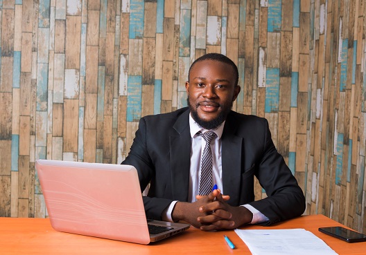 A financial adviser sits at a desk in his office and gets ready to meet with a client.