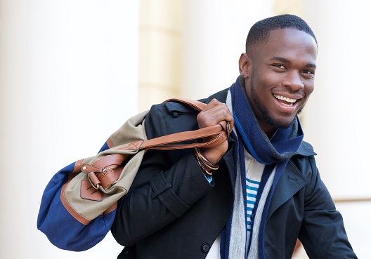 A young man smiles and prepares to leave for a trip covered by travel insurance.