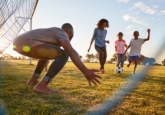 A young Ghanaian family enjoy playing soccer together at a local field.
