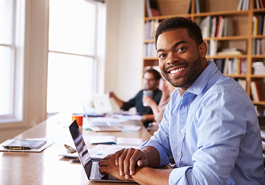 A young man enjoys studying an online financial education course at the library.