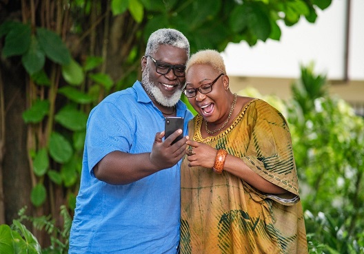 An elderly couple spend their retirement together and take a photo outdoors.