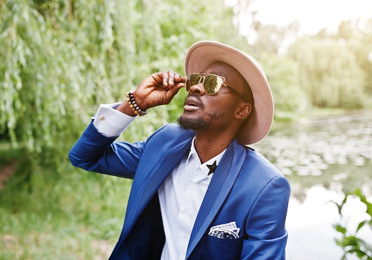A Ghanaian man wearing sunglasses looks up towards the sun.