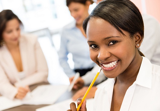 A female financial adviser smiles with her colleagues during an office meeting.