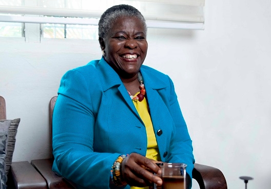 An elderly woman sits and enjoys a cup of tea.