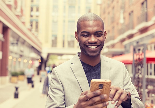 A Ghanaian man goes online on his phone to look up the address of a nearby Old Mutual branch.
