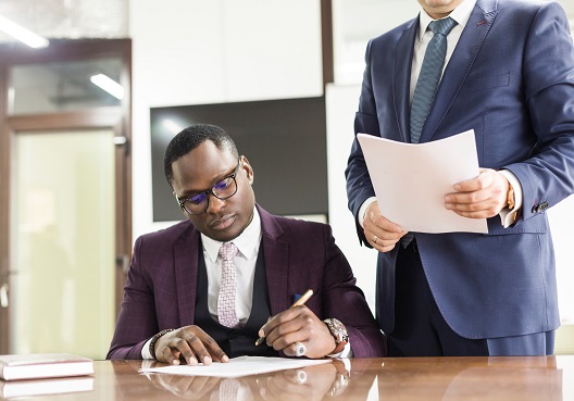 An adviser assists his client with the signing of his documentation.