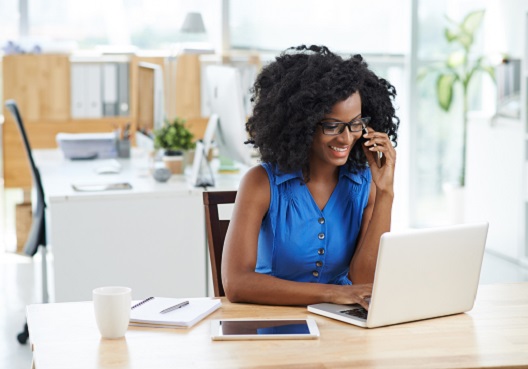 A woman uses a computer and calls an adviser to ask questions about pension plans.