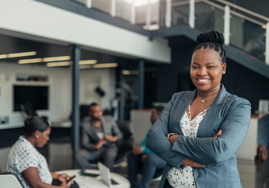 A Ghanaian woman dressed professionally smiles for a photo at the office.