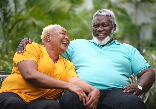 An older couple sit on a bench and enjoy the outdoors together.