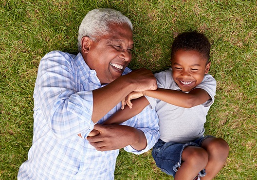 A grandfather plays with his grandchild and enjoys spending time with him outdoors.