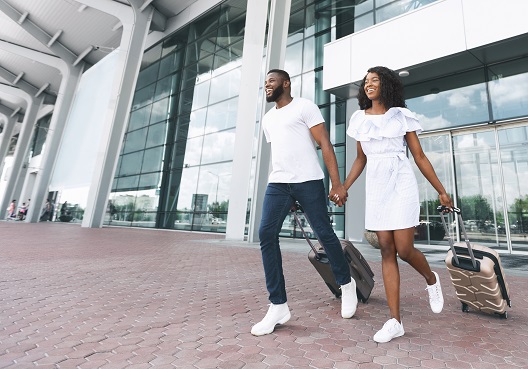 A Ghanaian couple leave an airport with their luggage after arriving for an international vacation.